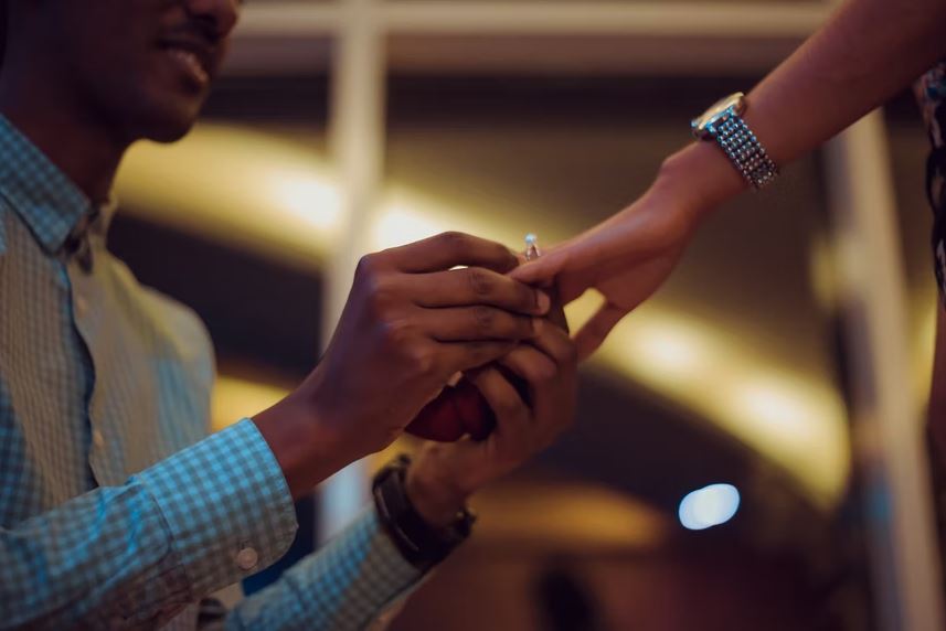 man putting on an engagement ring on a woman’s finger