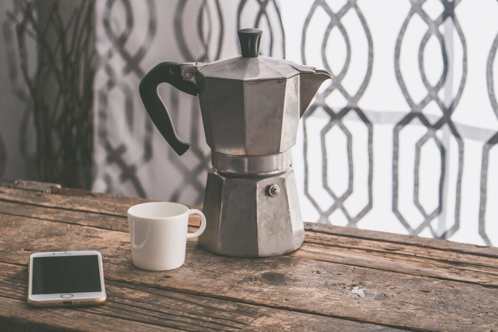gray-moka-pot-beside-white-ceramic-cup-on-brown-wooden-table