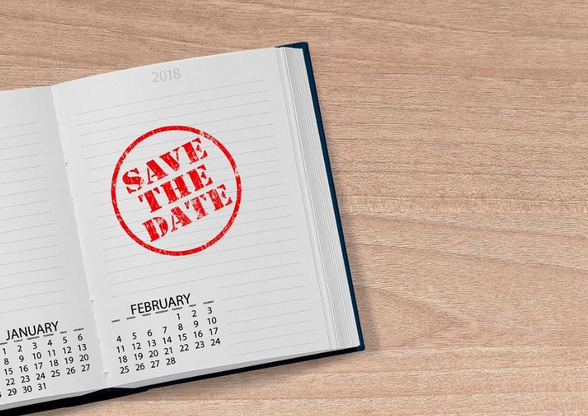 open planner, calendar, “Save the Date” sign, wood table