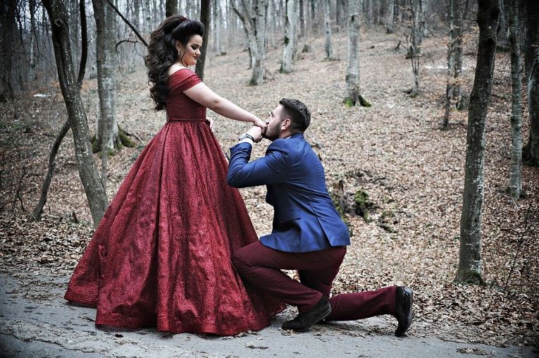 a man kissing a woman’s hand while kneeling as an act of having a proposal