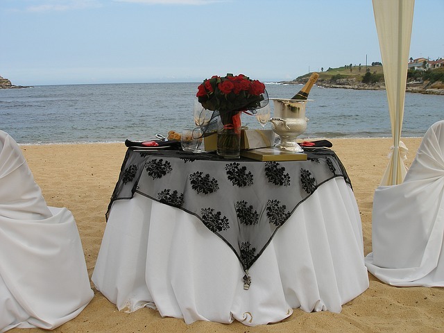 an engagement setting beside the beach, a table with bouquet, wine, wine glasses